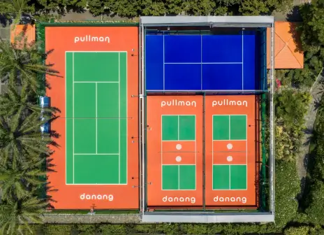 Aerial view of the blue padel court under its retractable roof, beside a tennis court and two pickleball courts